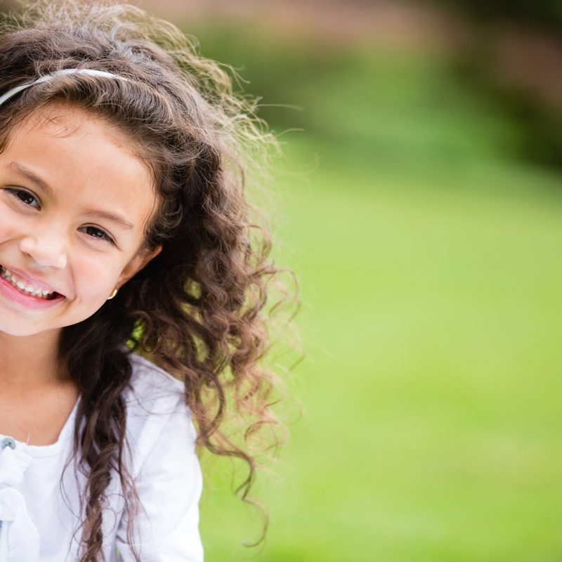 Smiling young girl with curly hair outdoors