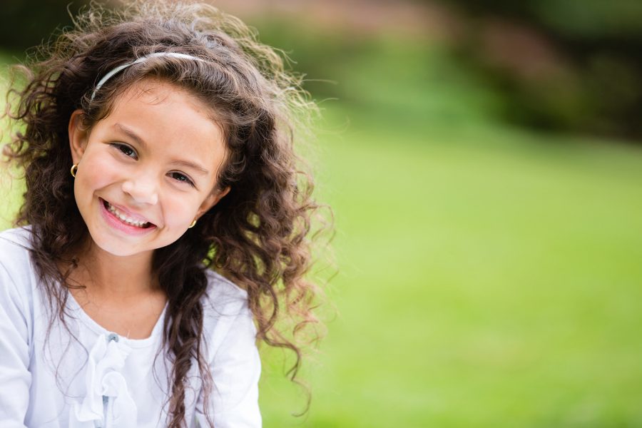 Smiling young girl with curly hair outdoors