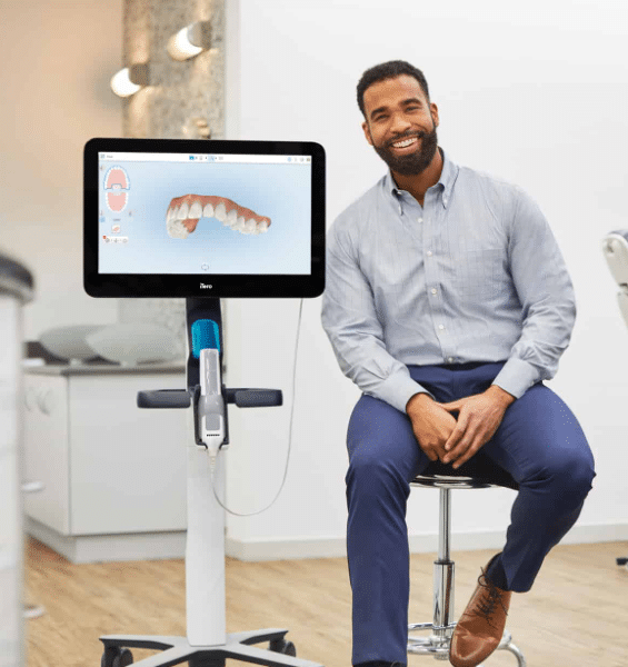 Dentist smiling beside digital dental scan display.