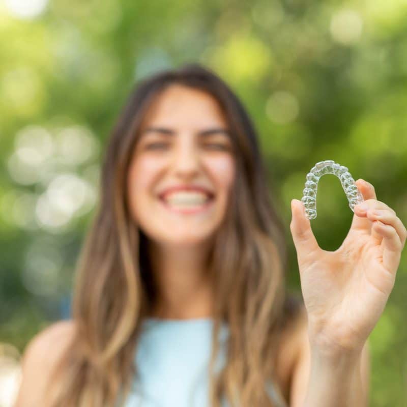 invisalign girl smiling holding invisalign, straighten your smile with invisalign