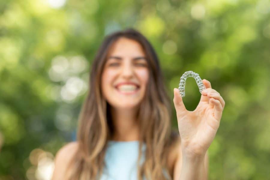 invisalign girl smiling holding invisalign, straighten your smile with invisalign